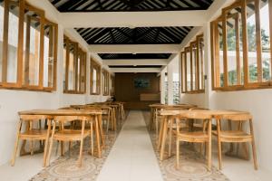 a row of tables and chairs in a room with windows at The Umbu Stay Banyuwangi in Banyuwangi
