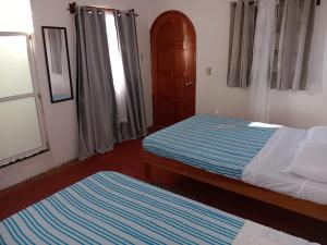 a bedroom with two beds with blue and white sheets at Casa Tzipora in Brisas de Zicatela