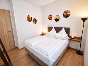 a bedroom with a white bed and some plates on the wall at Bernsteinsee Homes and Ferien Beach House 2 in Sassenburg