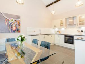 a kitchen with a glass table with a vase of flowers at Marigold in Shepton Mallet