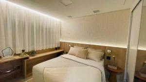 a bedroom with a white bed and a desk and window at Studio home office Inteligente Com Alexa no Coração do Shopping in Mogi das Cruzes