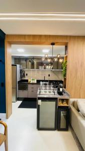 a kitchen with a stove and a couch in a room at Studio home office Inteligente Com Alexa no Coração do Shopping in Mogi das Cruzes +16 photos