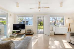 a living room with a couch and a tv at Beauts - Pet Friendly - 5 Mins Walk to Beach in Culburra Beach