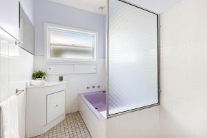 a bathroom with a purple tub and a sink at Beauts - Pet Friendly - 5 Mins Walk to Beach in Culburra Beach +18 photos