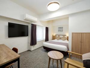 a hotel room with a bed and a flat screen tv at HOTEL MYSTAYS Kiyosumi Shirakawa in Tokyo