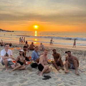 a group of people sitting on the beach at sunset at Casa Tzipora in Brisas de Zicatela