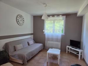 a living room with a couch and a tv at Le Hameau des Cardenals in Salviac