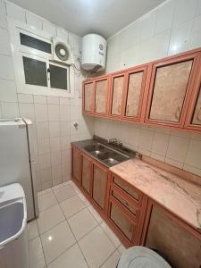 a small kitchen with wooden cabinets and a sink at الكرامة للشقق المفروشة in Abha