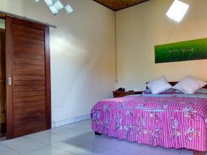 una camera con letto rosa e porta in legno di Rusma House Ubud ad Ubud