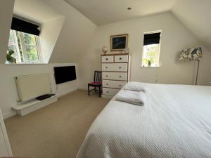 a bedroom with a white bed and a tv at Silsoe B&B Master Suite in Silsoe
