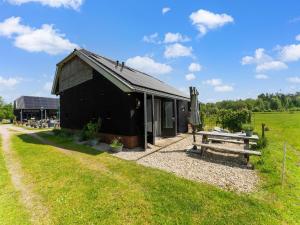a black building with a picnic table and a bench at Cottage in Dwingelderveld with Scenic Views in Beilen