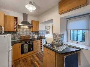 a kitchen with wooden cabinets and a sink and a window at Rubylea in Dumfries