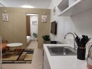 a kitchen with a sink and a living room at SMDC Trees Residences Jim's Staycation in Manila +28 photos