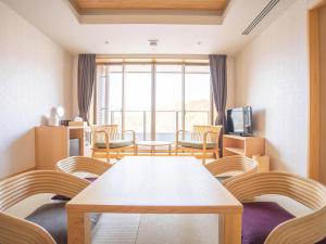 a room with a table and chairs and a tv at さめうら荘レイクサイドホテル in Tosa