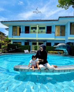 a woman and a child sitting next to a swimming pool at Kencana INN in Bandungan