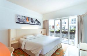 a bedroom with a white bed and a large window at New Jimbaran Hotel in Ungasan