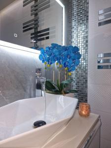 a vase with blue flowers sitting on a bathroom sink at Angel in Kołobrzeg +98 photos