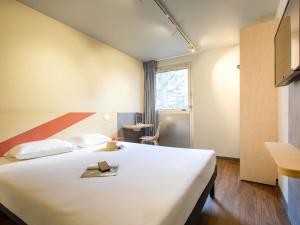 a bedroom with a large white bed and a window at ibis budget Avignon Centre in Avignon +50 photos