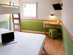 a bedroom with a bed and a desk with a laptop at ibis budget Avignon Centre in Avignon