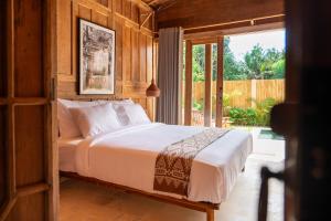 a bedroom with a bed and a sliding glass door at Taman Jati in Gili Islands