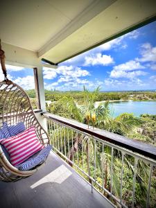 a balcony with a rattan chair and a view of a river at Lazy Days Penthouse - Opposite Shaws Bay - 180 Waterfront Views in East Ballina