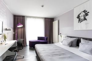 a bedroom with a bed and a desk and a chair at elaya hotel wolfenbuettel, Trademark Collection by Wyndham in Wolfenbüttel +6 photos