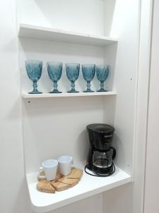 a shelf with four blue glass cups and a coffee maker at Apartamento 2QTS aconchegante in Vila Velha