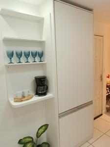 a white kitchen with blue glass vases on shelves at Apartamento 2QTS aconchegante in Vila Velha