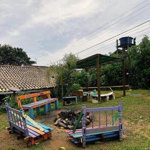 a group of park benches sitting in a yard at Hostel Pantera do Rosa in Praia do Rosa