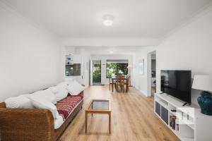 a living room with a couch and a tv at Garden Cottage Noraville in Toukley