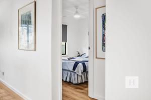 a white room with a bed and a bedroom door at Garden Cottage Noraville in Toukley