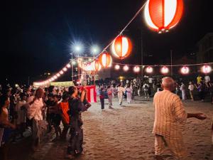 a crowd of people standing on a beach at night at Locanda L`altra Cucina in Yokosuka