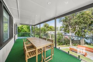 a dining room with a table and chairs on a balcony at Sunset Shore Retreat in Summerland Point