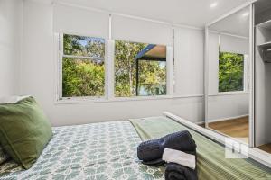 a bedroom with a bed and two windows at Sunset Shore Retreat in Summerland Point