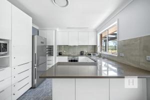 a kitchen with white cabinets and a stainless steel refrigerator at Jilliby Honey Farm in Jilliby