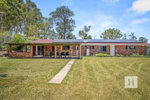 a brick house with a lawn in front of it at Jilliby Honey Farm in Jilliby