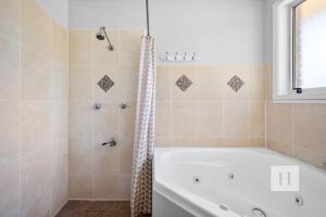 a bathroom with a white tub and a shower at Jilliby Honey Farm in Jilliby +7 photos