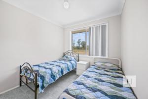 two beds in a room with a window at Jilliby Honey Farm in Jilliby