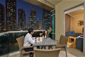 杜拜的住宿－Oaks Liwa Heights Hotel Suites，坐在阳台上桌子上的男人和女人