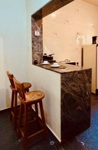 a kitchen with a counter and two stools in it at Pousada Flat Royal - Flat 03 in Itapecerica