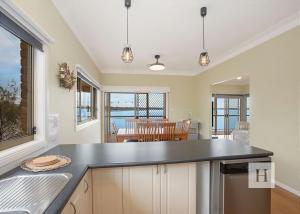 a kitchen with a black counter top and a dining room at Tide view in Toukley