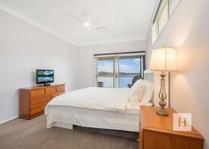 a white bedroom with a bed and a window at Tide view in Toukley