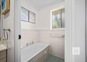 a white bathroom with a tub and a sink at Pete's Retreat -500m from the beach in Norah