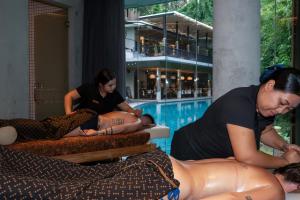 a group of people laying on beds next to a swimming pool at The Ning Resort Ubud in Ubud