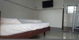 a bedroom with a bed and a tv on the wall at Nhà Nghỉ La Gi in Lagi