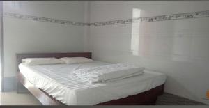 a bed with white sheets and pillows in a room at Nhà Nghỉ La Gi in Lagi