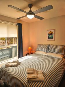 a bedroom with a large bed with a ceiling fan at Summer Villa in Kiama