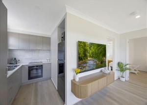 a kitchen with a large tv on the wall at Frangipani Hideaway in Budgewoi