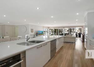 a kitchen with white counter tops and a living room at Enjoy Lazy Daze in Summerland Point