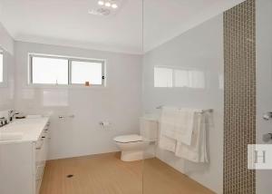 a white bathroom with a toilet and a sink at Enjoy Lazy Daze in Summerland Point +12 photos